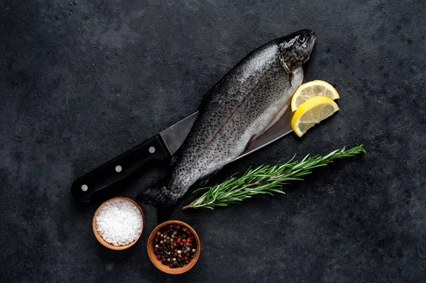 Taş zeminde baharat ve malzemelerle çiğ balık alabalığı.