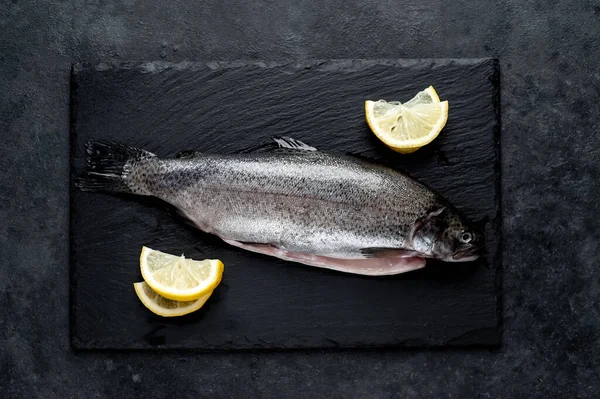 Taş zeminde baharat ve malzemelerle çiğ balık alabalığı.