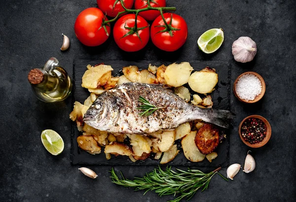 Kayalık zeminde kızarmış Dorado balığı ve patates.