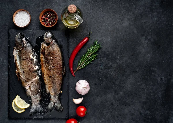 Taş zeminde baharat ve malzemelerle kızarmış balık alabalığı.