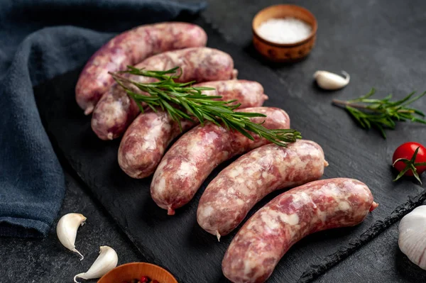 Izgara için çiğ sosis ve arka plandaki kesme tahtasındaki baharatlar.