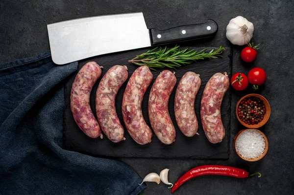Izgara için çiğ sosis ve arka plandaki kesme tahtasındaki baharatlar.