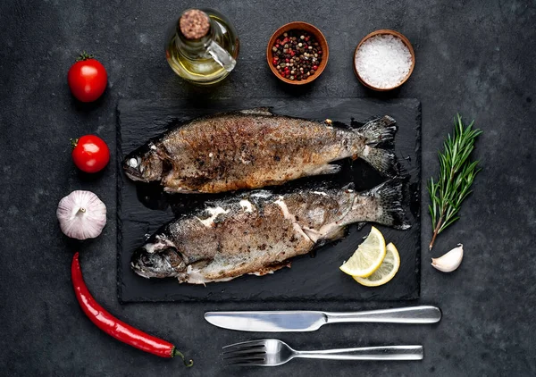 Taş zeminde baharat ve malzemelerle kızarmış balık alabalığı.