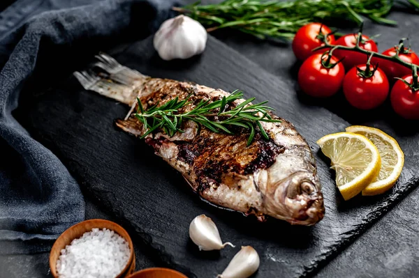 Limonlu ve biberiyeli sazan balığı. Taş zeminde bir tahta üzerinde.