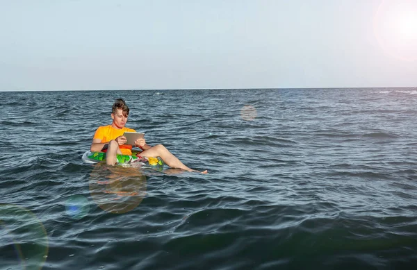 Suda şişme yüzük tabletli bir adam.