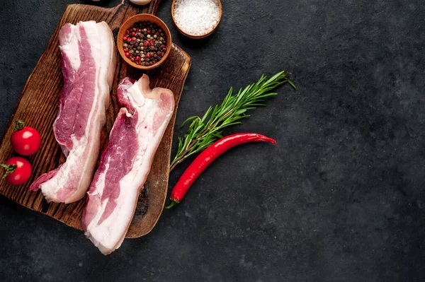 Metnin için fotokopi alanı olan taştan bir arka planda kesilmiş baharatlı çiğ domuz göğsü.