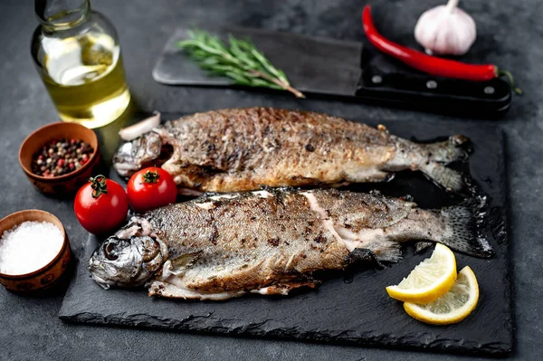 Taş zeminde baharat ve malzemelerle kızarmış balık alabalığı.