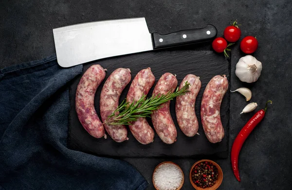 Izgara için çiğ sosis ve arka plandaki kesme tahtasındaki baharatlar.
