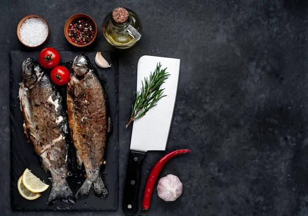 Taş zeminde baharat ve malzemelerle kızarmış balık alabalığı.