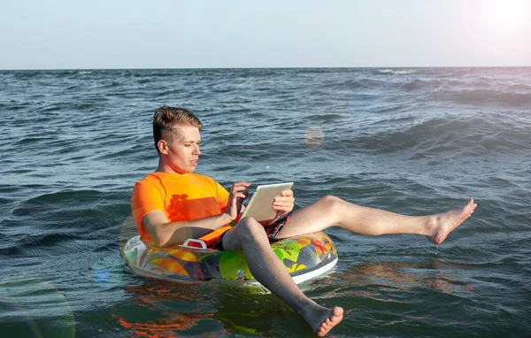 Suda şişme yüzük tabletli bir adam.