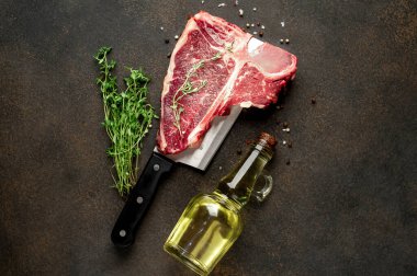 Taştan arka planda et bıçağındaki malzemelerle birlikte çiğ biftek yakın plan görüntüsü.