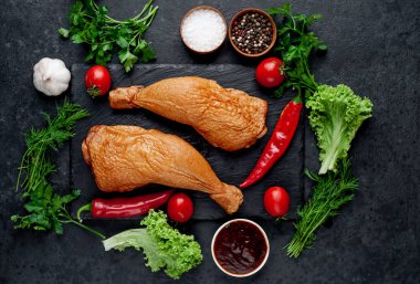 Arka planda baharat olan tütsülenmiş tavuk butları.