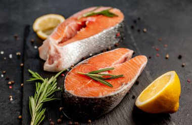 Çiğ balık somon bifteği ve taştan bir arka planda malzemeler.