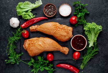 Arka planda baharat olan tütsülenmiş tavuk butları.