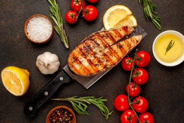 Izgara somon bifteği, arka planda et bıçağının üzerinde malzemeler var.