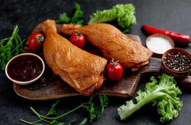 Arka planda baharat olan tütsülenmiş tavuk butları.