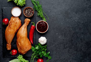 Arka planda baharat olan tütsülenmiş tavuk butları.