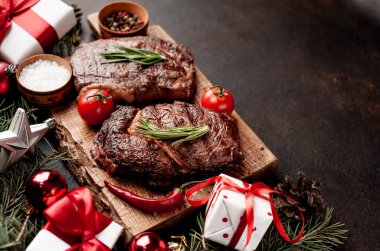İki kişilik Noel yemeği, ızgara biftek, pirzola, yeşillik ve baharatlar bir taş masanın üzerinde Noel ağacı ve yeni yıl oyuncakları süslemesi.