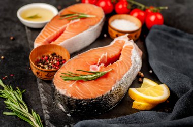 Çiğ balık somon bifteği ve taştan bir arka planda malzemeler.