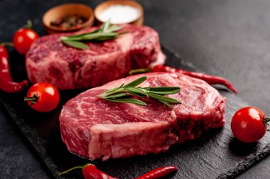 Arka planda baharatlı iki çiğ biftek.