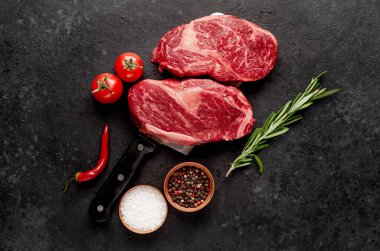 Taştan bir arka planda et bıçağında iki çiğ biftek.