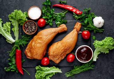 Arka planda baharat olan tütsülenmiş tavuk butları.