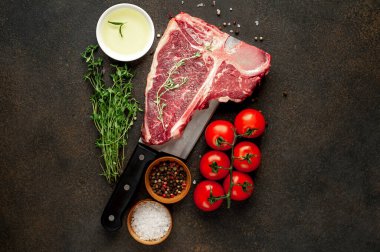 Taştan arka planda et bıçağındaki malzemelerle birlikte çiğ biftek yakın plan görüntüsü.