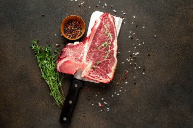 Taştan arka planda et bıçağındaki malzemelerle birlikte çiğ biftek yakın plan görüntüsü.