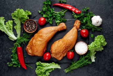 Arka planda baharat olan tütsülenmiş tavuk butları.