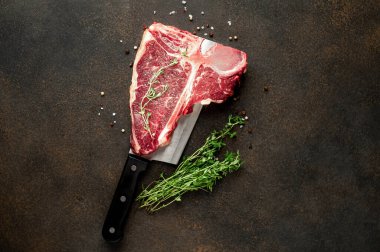 Taştan arka planda et bıçağındaki malzemelerle birlikte çiğ biftek yakın plan görüntüsü.