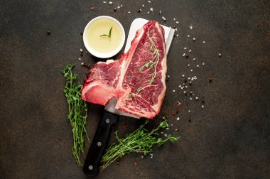 Taştan arka planda et bıçağındaki malzemelerle birlikte çiğ biftek yakın plan görüntüsü.