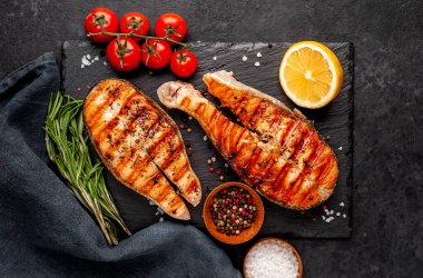 Izgara somon bifteği ve taştan bir arka planda malzemeler.