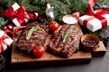 İki kişilik Noel yemeği, ızgara biftek, pirzola, yeşillik ve baharatlar bir taş masanın üzerinde Noel ağacı ve yeni yıl oyuncakları süslemesi.