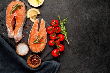 Çiğ balık somon bifteği ve taştan bir arka planda malzemeler.