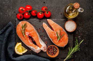 Çiğ balık somon bifteği ve taştan bir arka planda malzemeler.