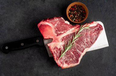 Taştan arka planda et bıçağındaki malzemelerle birlikte çiğ biftek yakın plan görüntüsü.