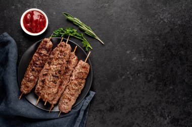 Lezzetli ızgara Lula kebapları şiş ve baharatlar arka planda.