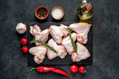 Baharatlı tavuk kanatları, biber biberi ve siyah taş arka planda biberiye dalları.