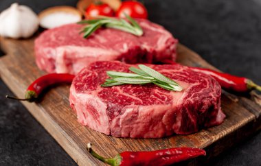 Arka planda baharatlı iki çiğ biftek.