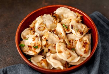 Taştan bir arka planda kabın içinde haşlanmış lahana ile doldurulmuş hamur tatlısı.