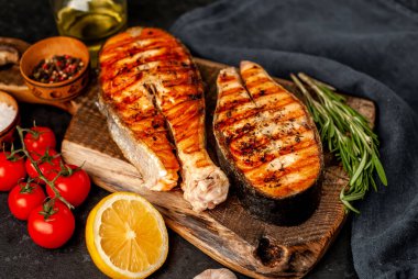 Izgara somon bifteği ve taştan bir arka planda kesim tahtası malzemeleriyle yakın plan görüntüsü.