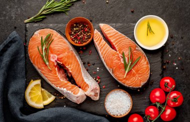 Çiğ balık somon bifteği ve taştan bir arka planda malzemeler.