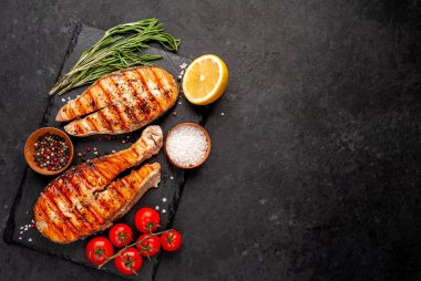 Izgara somon bifteği ve taştan bir arka planda malzemeler.