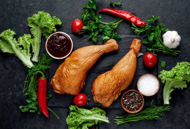 Arka planda baharat olan tütsülenmiş tavuk butları.