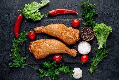 Arka planda baharat olan tütsülenmiş tavuk butları.