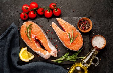 Çiğ balık somon bifteği ve taştan bir arka planda malzemeler.