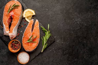 Çiğ balık somon bifteği ve taştan bir arka planda malzemeler.