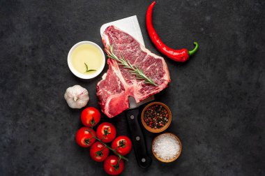Taştan arka planda et bıçağındaki malzemelerle birlikte çiğ biftek yakın plan görüntüsü.
