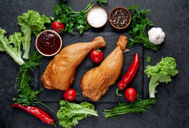 Arka planda baharat olan tütsülenmiş tavuk butları.