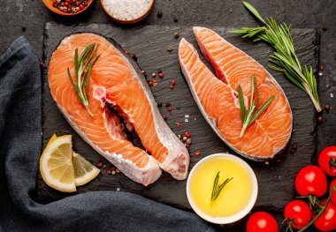 Çiğ balık somon bifteği ve taştan bir arka planda malzemeler.